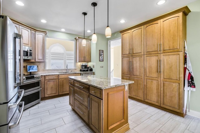 kitchen featuring pendant lighting, a center island, sink, light stone countertops, and stainless steel appliances