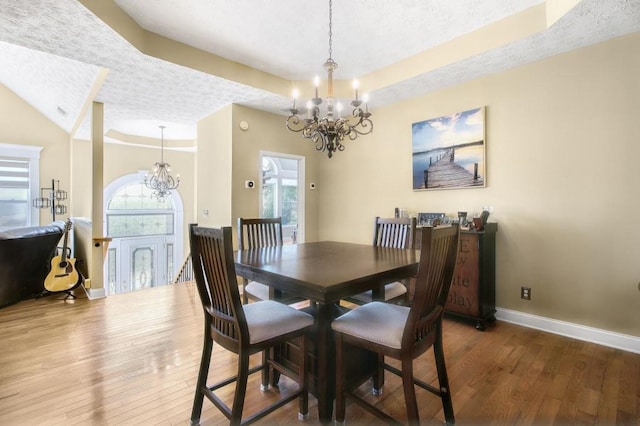 dining space with hardwood / wood-style floors, a textured ceiling, an inviting chandelier, and a healthy amount of sunlight