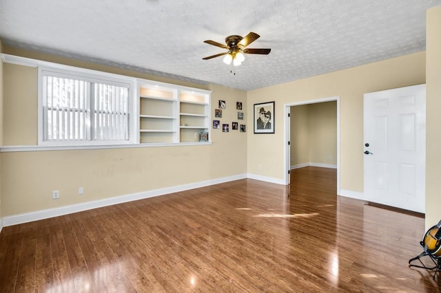 interior space featuring built in shelves, a textured ceiling, ceiling fan, and dark wood-type flooring