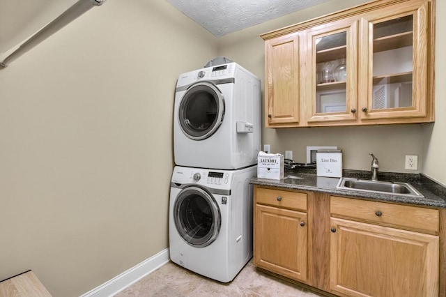 washroom with sink, light tile patterned floors, cabinets, and stacked washer / drying machine