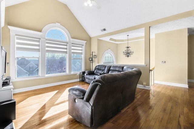 living room featuring high vaulted ceiling, ceiling fan with notable chandelier, and hardwood / wood-style flooring