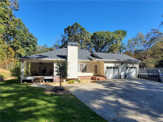 rear view of house with a garage, a yard, and ceiling fan