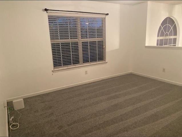 spare room featuring dark carpet