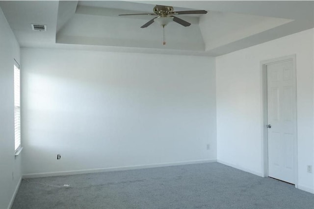 carpeted empty room featuring ceiling fan and a tray ceiling