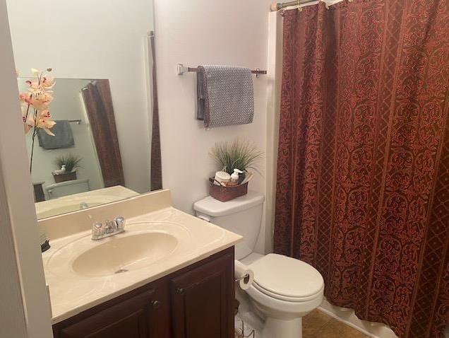 bathroom with toilet, vanity, and tile patterned flooring