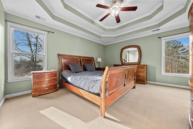 bedroom featuring a tray ceiling, ornamental molding, light colored carpet, and ceiling fan