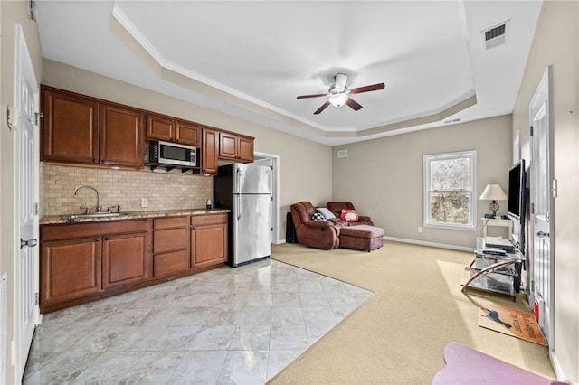 kitchen with sink, tasteful backsplash, appliances with stainless steel finishes, a raised ceiling, and ceiling fan