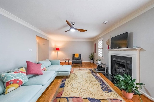 living area featuring a ceiling fan, a fireplace with flush hearth, wood finished floors, and baseboards