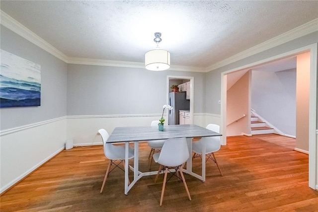 dining area with stairway, a textured ceiling, crown molding, and wood finished floors