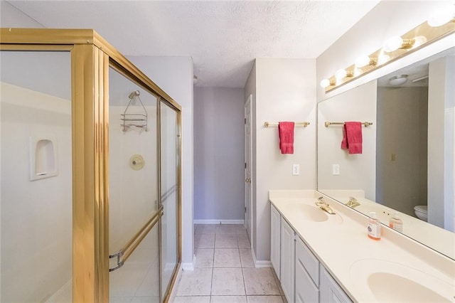 bathroom featuring tile patterned flooring, double vanity, a stall shower, a textured ceiling, and a sink