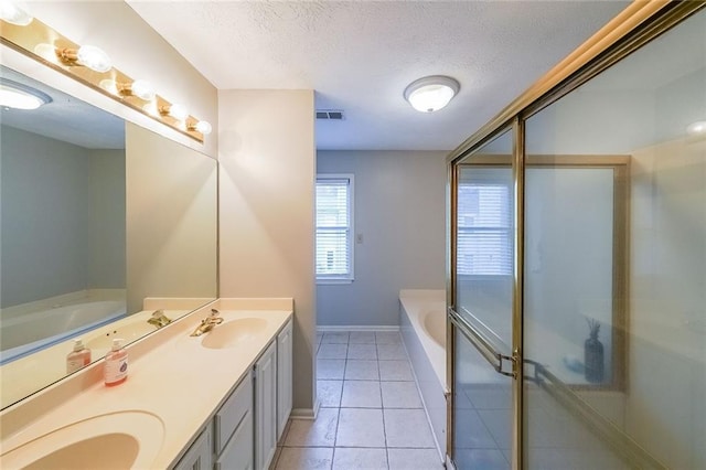 bathroom with visible vents, double vanity, a sink, a textured ceiling, and a garden tub