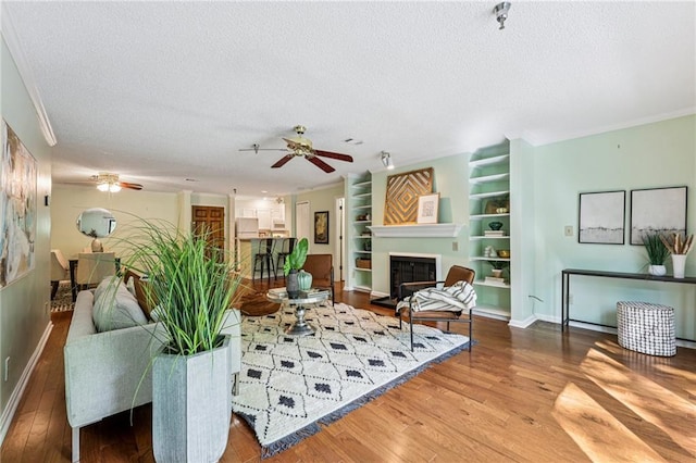 302 Ridley Howard Ct Unit 302, Decatur, GA 30030 - living area featuring a textured ceiling, ceiling fan, wood finished floors, a glass covered fireplace, and built in shelves