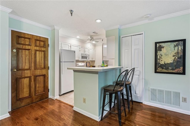 302 Ridley Howard Ct Unit 302, Decatur, GA 30030 - kitchen featuring white appliances, a breakfast bar, white cabinetry, ornamental molding, and wood finished floors