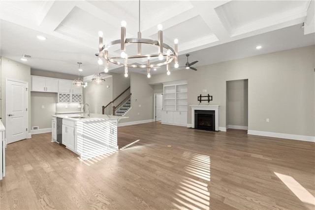 unfurnished living room featuring baseboards, recessed lighting, coffered ceiling, ceiling fan with notable chandelier, and beamed ceiling
