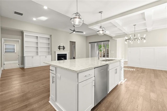 kitchen featuring a sink, dishwasher, beamed ceiling, light wood finished floors, and visible vents