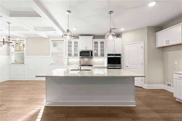 kitchen featuring white cabinets, appliances with stainless steel finishes, a sink, and beamed ceiling
