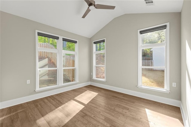 unfurnished room featuring lofted ceiling, wood finished floors, visible vents, a ceiling fan, and baseboards