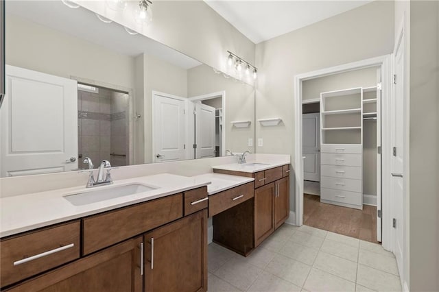 full bathroom featuring tile patterned floors, vanity, a walk in closet, and a tile shower