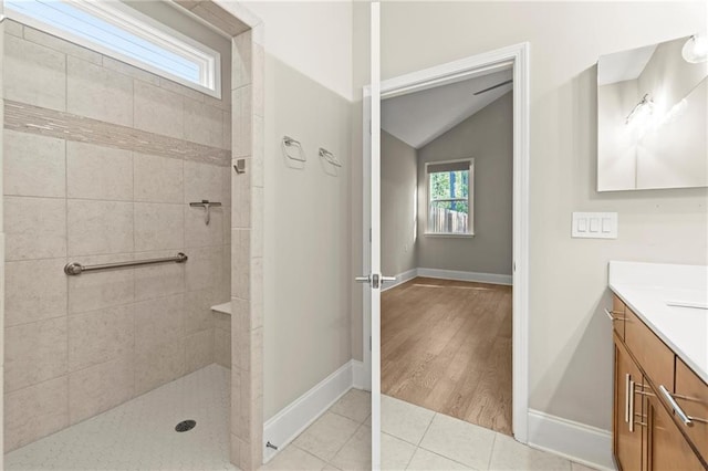 bathroom featuring baseboards, walk in shower, vaulted ceiling, and vanity