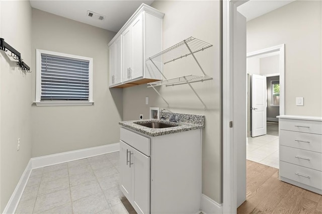 laundry room with a sink, baseboards, visible vents, washer hookup, and cabinet space
