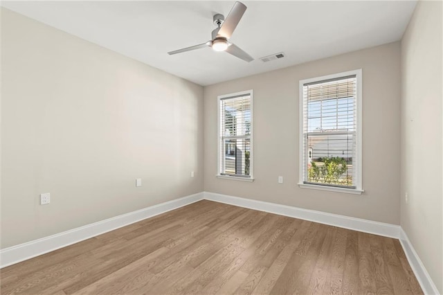 spare room featuring ceiling fan, baseboards, wood finished floors, and visible vents