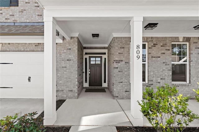 view of exterior entry with brick siding and covered porch