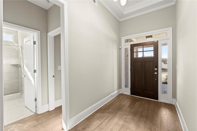 foyer with light wood-style flooring, baseboards, and ornamental molding