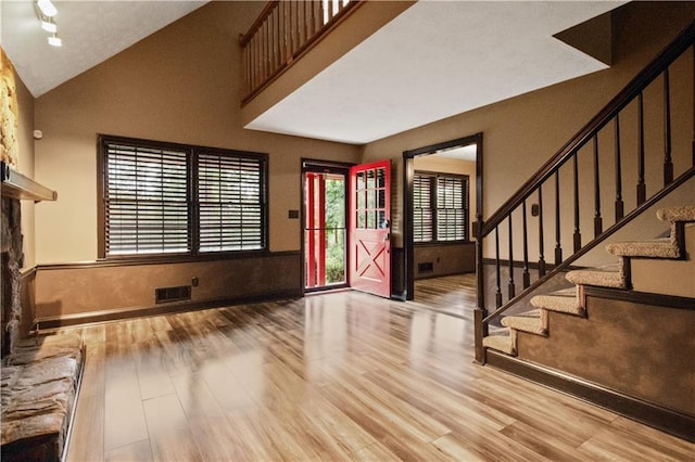 6945 Butner Rd, Atlanta, GA 30349 - foyer with high vaulted ceiling, a stone fireplace, wood finished floors, visible vents, and stairway