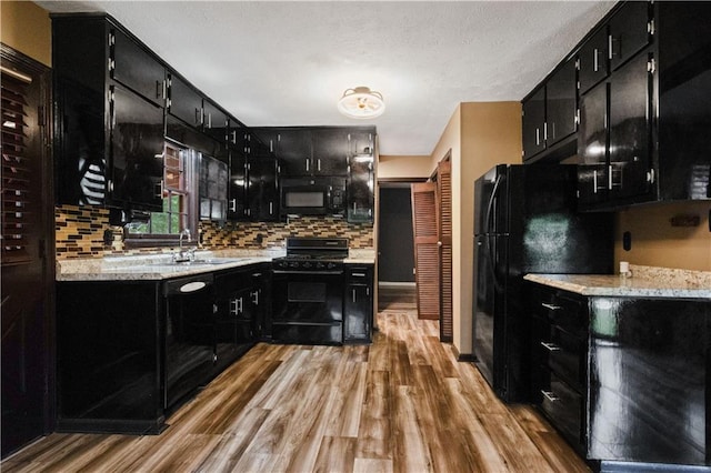 6945 Butner Rd, Atlanta, GA 30349 - kitchen featuring dark cabinetry, a sink, black appliances, and light wood-type flooring