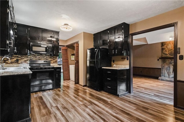 6945 Butner Rd, Atlanta, GA 30349 - kitchen featuring dark cabinetry, a sink, black appliances, and light wood-type flooring