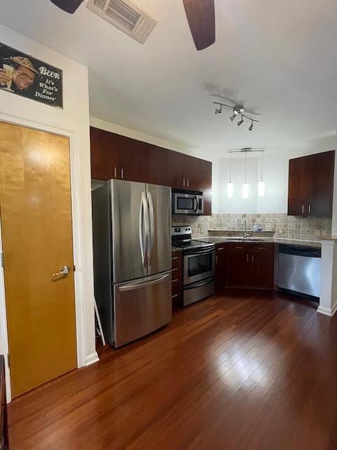 kitchen featuring decorative backsplash, appliances with stainless steel finishes, dark hardwood / wood-style floors, and decorative light fixtures