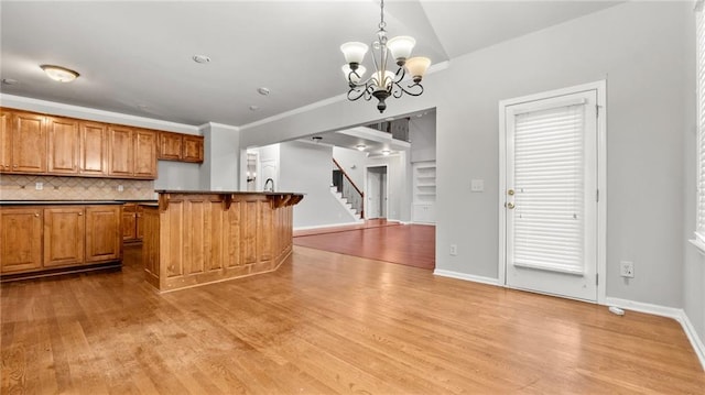 kitchen featuring light wood-type flooring, dark countertops, brown cabinets, and backsplash