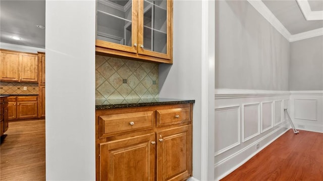 bar with a decorative wall, a wainscoted wall, dark wood-style flooring, ornamental molding, and tasteful backsplash