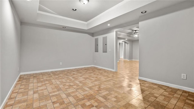 spare room with a tray ceiling, arched walkways, ornamental molding, electric panel, and baseboards