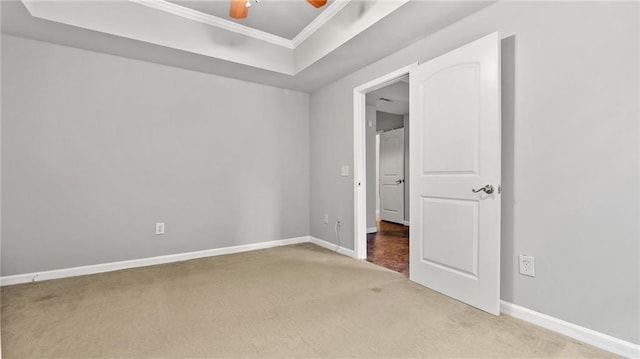 unfurnished bedroom featuring crown molding, carpet floors, a tray ceiling, and baseboards