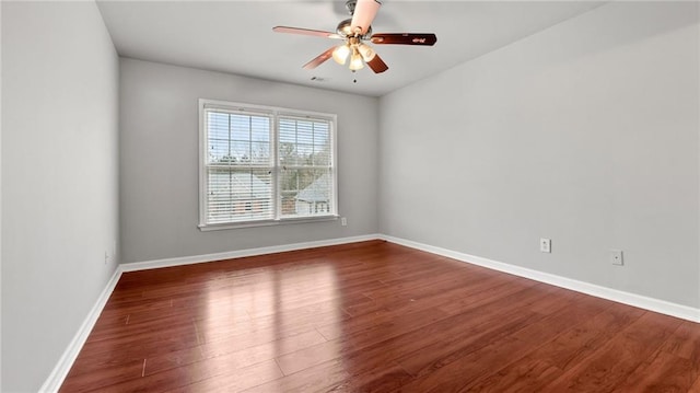 empty room with ceiling fan, visible vents, baseboards, and wood finished floors