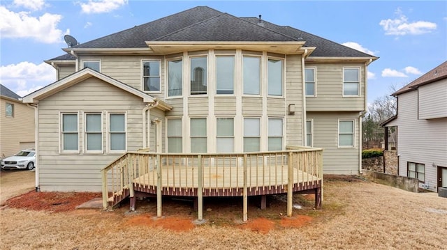 rear view of house featuring a shingled roof and a wooden deck