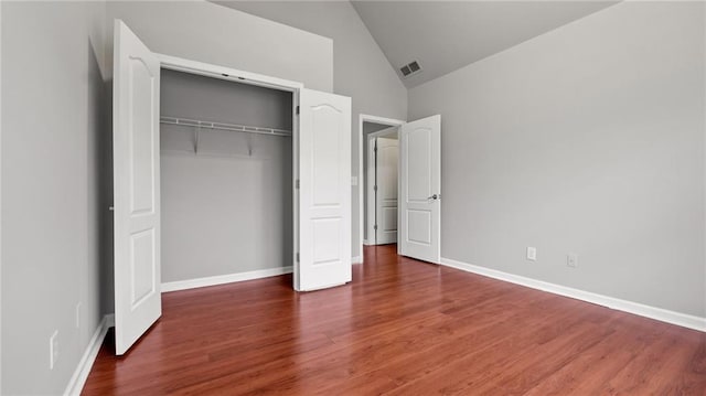 unfurnished bedroom with lofted ceiling, baseboards, visible vents, and wood finished floors