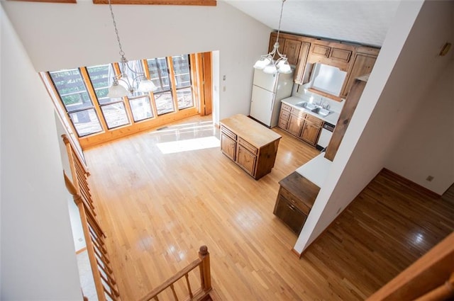 kitchen with light hardwood / wood-style floors, high vaulted ceiling, hanging light fixtures, and an inviting chandelier