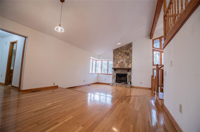 unfurnished living room with wood-type flooring, beam ceiling, high vaulted ceiling, a notable chandelier, and a fireplace