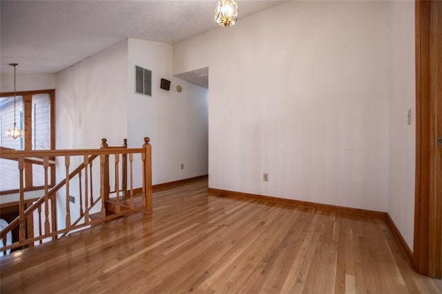 spare room with light hardwood / wood-style flooring and an inviting chandelier