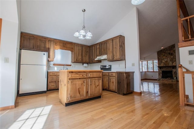 kitchen featuring high vaulted ceiling, white fridge, light hardwood / wood-style floors, decorative light fixtures, and a fireplace