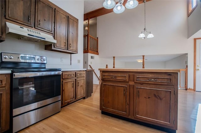 kitchen featuring stainless steel electric range oven, a high ceiling, an inviting chandelier, light hardwood / wood-style flooring, and pendant lighting