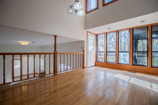 empty room featuring a chandelier, hardwood / wood-style floors, a textured ceiling, and a high ceiling