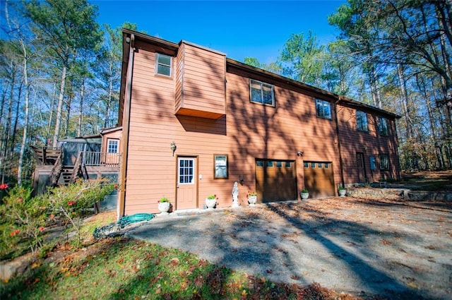 rear view of house featuring a deck and a garage