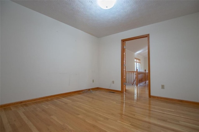 unfurnished room with a textured ceiling and light wood-type flooring