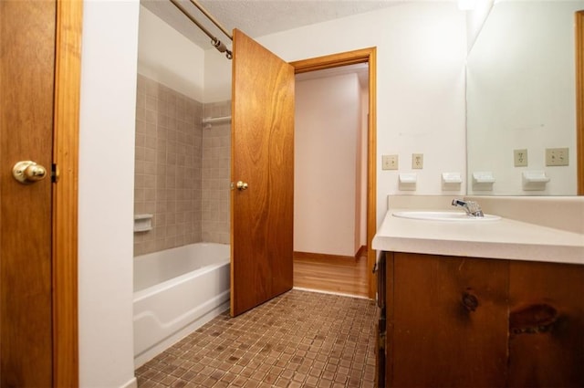 bathroom with hardwood / wood-style floors, vanity, and tiled shower / bath