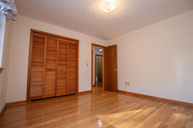 unfurnished bedroom with light hardwood / wood-style floors, a textured ceiling, and a closet