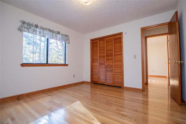 unfurnished bedroom featuring a closet, a textured ceiling, and light hardwood / wood-style flooring