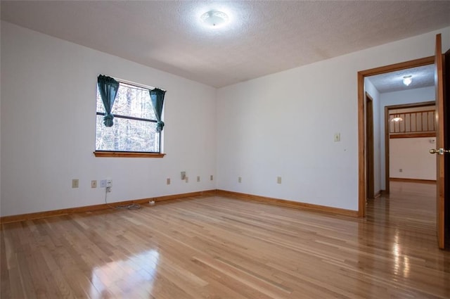 unfurnished room featuring light hardwood / wood-style floors and a textured ceiling